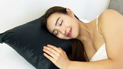 笑顔で横たわる女性と黒い枕